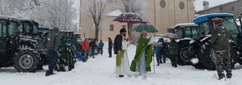 Il parroco don Piero Lombard, aiutato dal diacono Luciano Bonino, mentre impartisce la benedizione sotto la neve